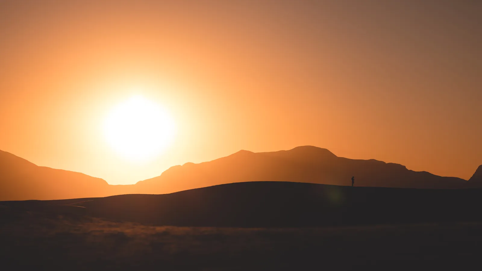 The low sun above a distant mountain ridge at White Sands National Park