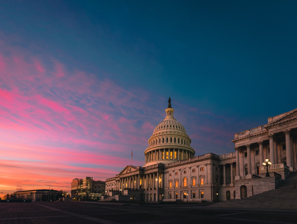 The east front of the US Capitol during morning blue hour, deep blue sky overhead with pink cirrus and an orange band at the horizon, the sun still below it